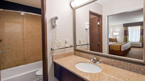 a bathroom with a sink and a mirror and a bed at Best Western - Fayetteville in Fayetteville