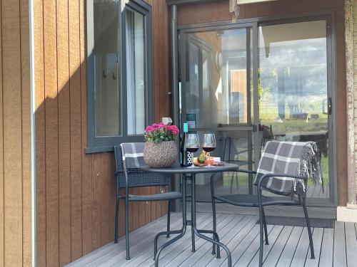 a table and two chairs on a porch with wine glasses at NEST- Luxury Vineyard Accommodation in Rowella