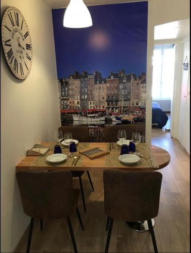 une table à manger avec des chaises et une horloge murale dans l'établissement Le logis des lavandières, à Honfleur