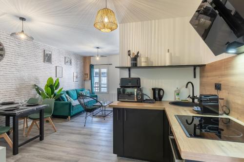 uma cozinha e sala de estar com um sofá e uma mesa em Vert d'Hotes - Charming renovated apartment - downtown - WIFI - em Honfleur
