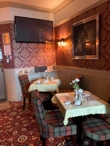 a restaurant with two tables and a tv on the wall at The Woodleigh family hotel in Blackpool