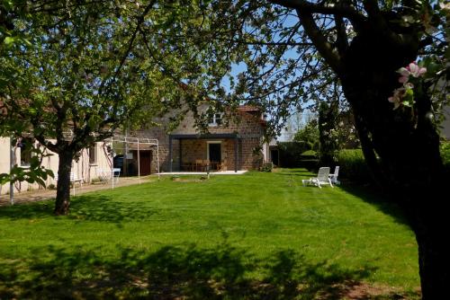 un patio con una casa de piedra con un árbol en L'Oustal des Bons Vivants, en Conques-en-Rouergue