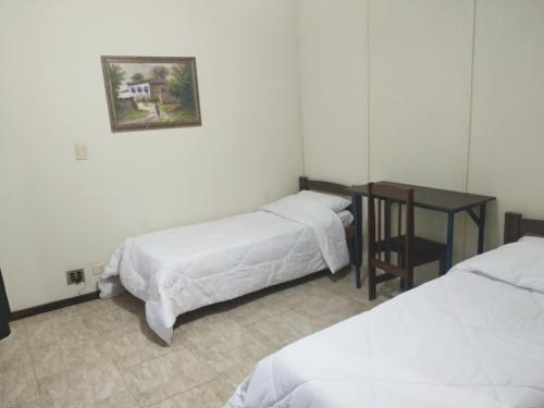 a room with three beds and a table and a picture at Hotel Veritas in Guarapuava