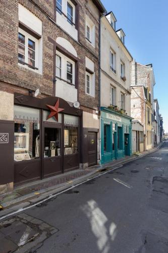 une rue avec un magasin avec une étoile rouge près de la fenêtre dans l'établissement Marée haute - nice refresh studio in a full center - Netflix - wifi -, à Honfleur