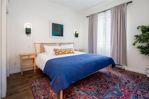 a bedroom with a bed with a blue blanket and a rug at Crazy Creek Resort in Malakwa