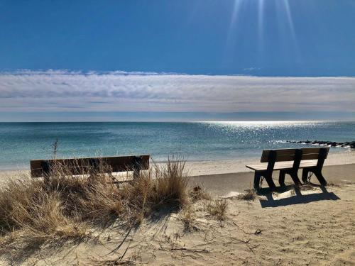two benches sitting on the beach near the ocean at Ocean Breeze Motel in South Yarmouth