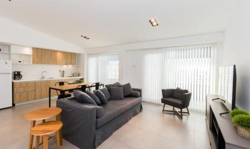 a living room with a gray couch and a kitchen at Austral Departamentos in Ushuaia