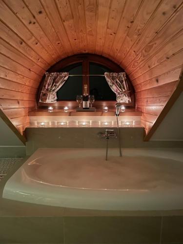 a bath tub in a room with a wooden ceiling at Willa Pod Strzechą in Wiartel Mały