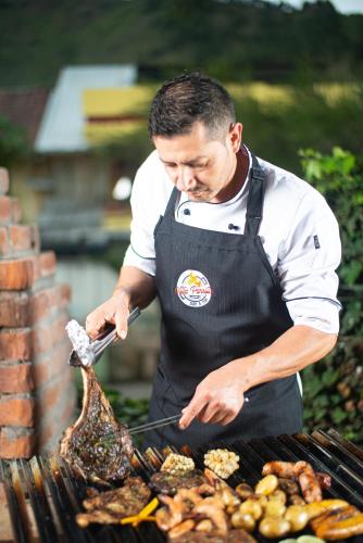 a man is cooking food on a grill at Hotel Tungurahua in Baños