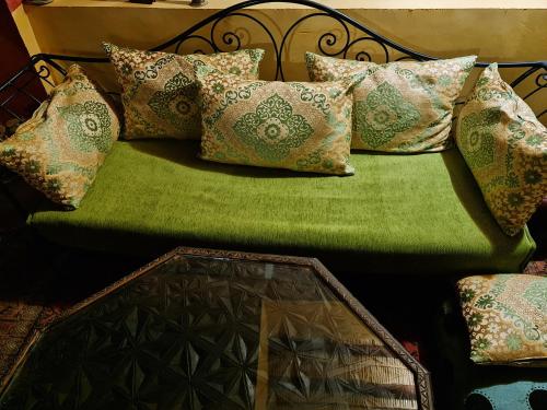 a green couch with many pillows on it at Chez Laila in Skoura