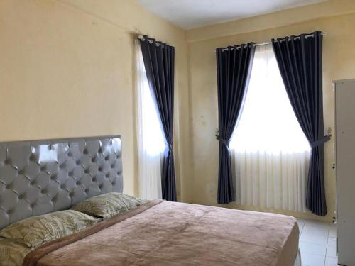 Telukjambe的住宿－Comfy Studio Emerald Hills，一间卧室设有一张床和两个窗户。