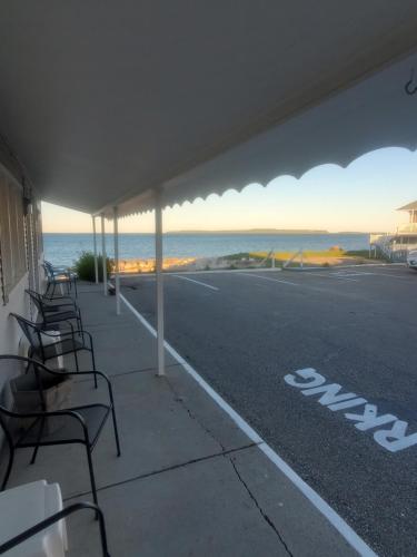a group of chairs sitting on a sidewalk next to the ocean at Bayview Lakefront Inn in Saint Ignace
