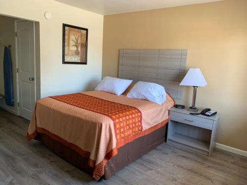 a bedroom with a bed and a lamp on a night stand at Redwood Inn in Santa Rosa