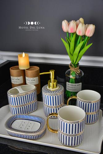 a tray with blue and white striped cups and a vase of flowers at Hotel Del Luna Boutique in Da Nang
