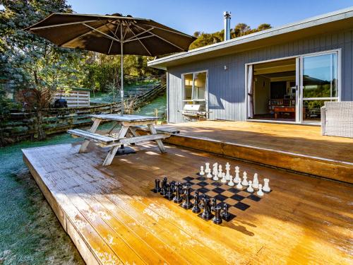 a chess game on a wooden deck with an umbrella at Pikorua - Raurimu Holiday Home in National Park