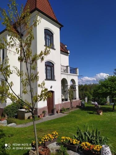 une grande maison blanche avec une tourelle ronde dans l'établissement Villa Liduška s kavárnou, à Bechyně