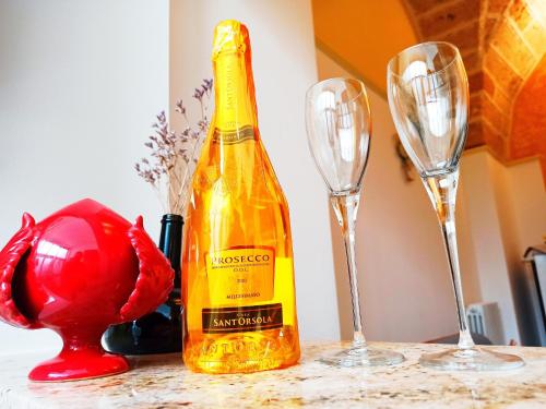 a yellow bottle of wine next to two wine glasses at Casa Amata Salentina in Squinzano