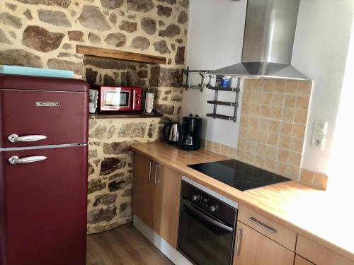 La cuisine est équipée d'un réfrigérateur rouge et d'un four micro-ondes. dans l'établissement Maison avec terrasse vue sur ria d'Etel - moulin du Sac'h, à Étel