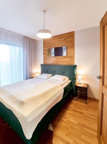 a bedroom with a large bed and a window at LAGUNA Apartament Polanica Residence 43 z garażem- SPA in Polanica-Zdrój
