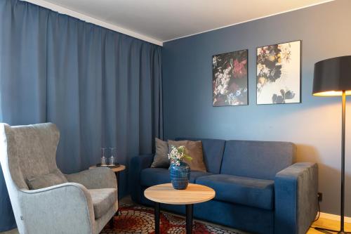 a living room with a blue couch and a chair at Elite Hotel Brage - Hotel & Spa in Borlänge