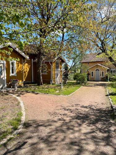ein gelbes Haus mit einem Baum und einer Einfahrt in der Unterkunft Taattisten Tila - Taattinen Farm and Cottages in Naantali