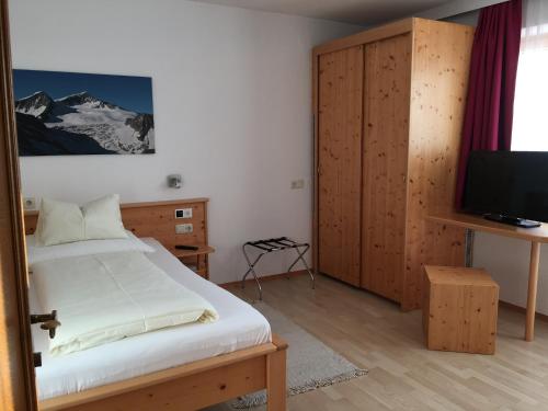 1 dormitorio con 1 cama y TV en Pension Kristall, en Bramberg am Wildkogel