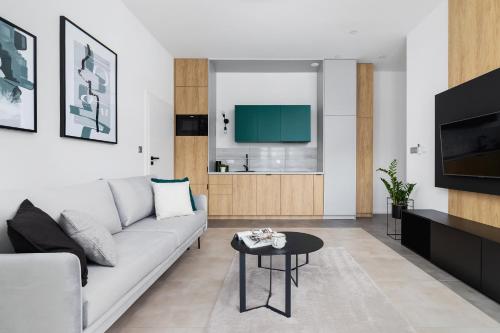 a living room with a white couch and a tv at EN Apartamenty in Podolsze