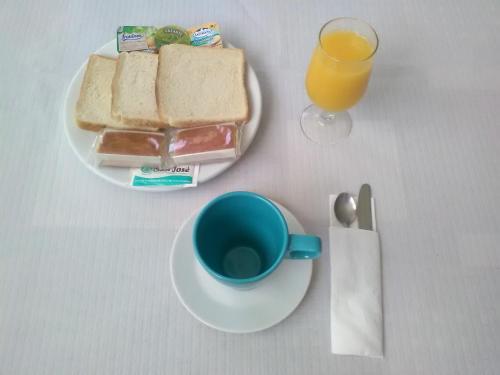 una mesa con un plato de sándwiches y una taza de zumo de naranja en Hotel Costa Cántabra, en Argoños