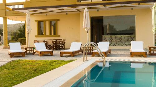 a patio with a pool and chairs and a house at Village View Afandou in Afantou