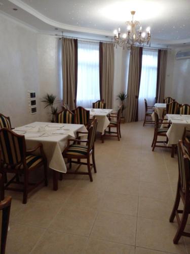 un comedor con mesas y sillas y una lámpara de araña en In hotel, en Kamianets-Podilskyi