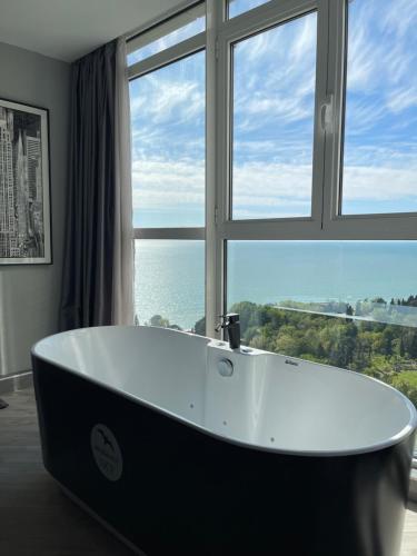 a bath tub in a bathroom with a large window at Residence Sky in Sochi
