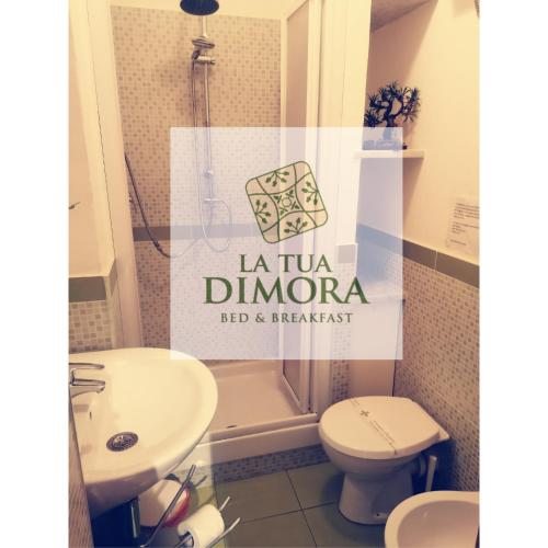 baño con lavabo, aseo y cartel en B&B La Tua Dimora, en Palermo