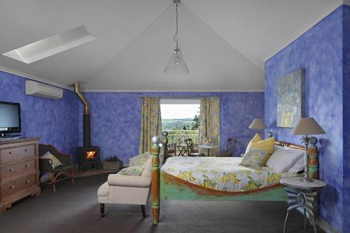 sypialnia z niebieskimi ścianami, łóżkiem i oknem w obiekcie The Spotted Chook and Amelie's Petite Maison w mieście Montville