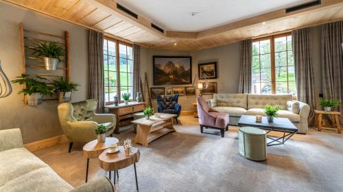 ein Wohnzimmer mit Sofas, Tischen und Fenstern in der Unterkunft Geniesserhotel Le Grand Chalet in Gstaad
