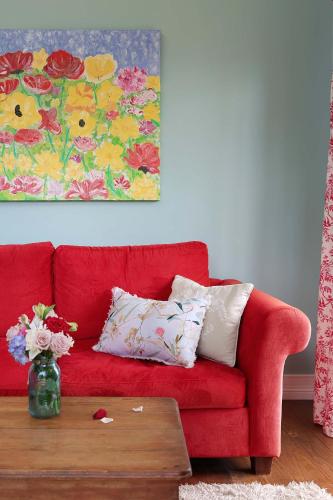 a red couch in a living room with a table at The Spotted Chook and Amelie's Petite Maison in Montville
