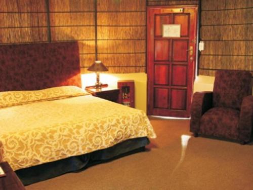a bedroom with a bed and a chair and a door at Kievits Kroon Gauteng Wine Estate in Pretoria