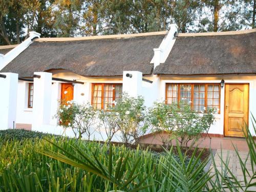 a white house with a thatched roof at Kievits Kroon Gauteng Wine Estate in Pretoria