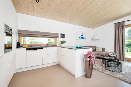 a kitchen with white cabinets and a couch at Apartment Velden - 24 Home im Zentrum in Velden am Wörthersee