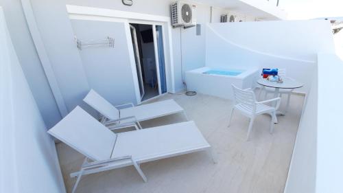 a white room with a table and chairs and a table and a tablektop at Naiades Marina Hotel in Agios Nikolaos
