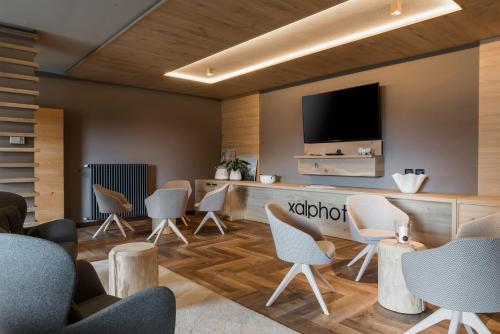 a waiting room with chairs and a flat screen tv at X Alp Hotel in Pozza di Fassa