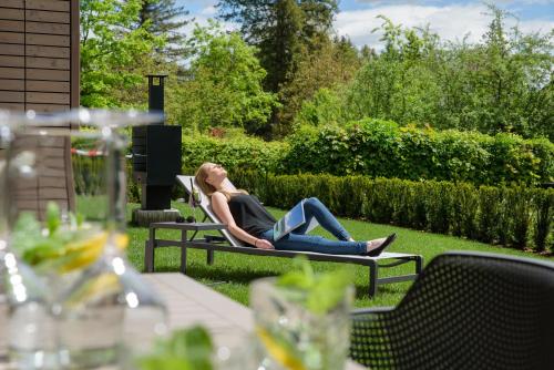 a woman sitting on a bench in a garden at Apartment Velden - 24 Home im Zentrum in Velden am Wörthersee
