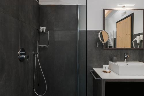 a bathroom with a shower and a sink and a mirror at X Alp Hotel in Pozza di Fassa
