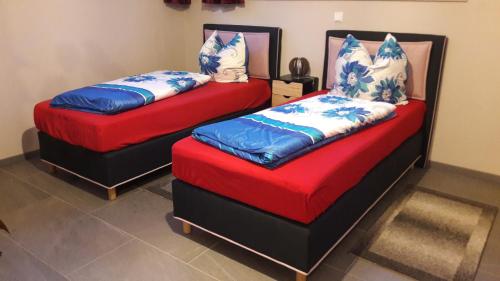 two beds with red and blue cushions in a room at Apartment Am Eck in Schmölln