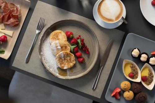 a table with a plate of food and a cup of coffee at X Alp Hotel in Pozza di Fassa