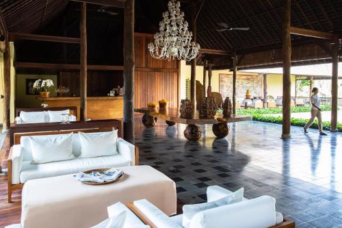 a living room with white furniture and a chandelier at Komaneka at Bisma Ubud in Ubud