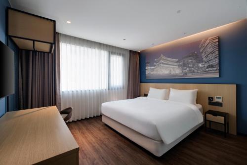a bedroom with a large white bed and a window at Travelodge Myeongdong City Hall in Seoul