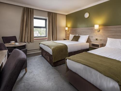 a hotel room with two beds and a chair at Treacys West County Conference and Leisure Centre in Ennis