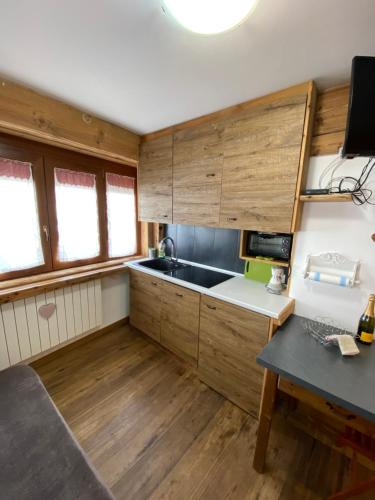 a small kitchen with wooden cabinets and a table at Bianca's apartments in Breuil-Cervinia