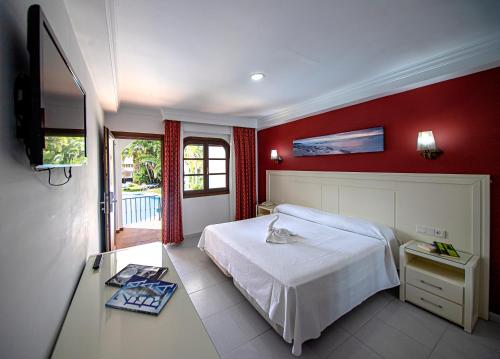 a bedroom with a white bed and a red wall at Hotel Pozo del Duque in Zahara de los Atunes