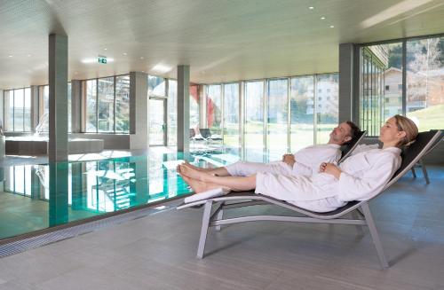 a man and woman sitting in a chair in a house at Pradas Resort Brigels in Breil/Brigels